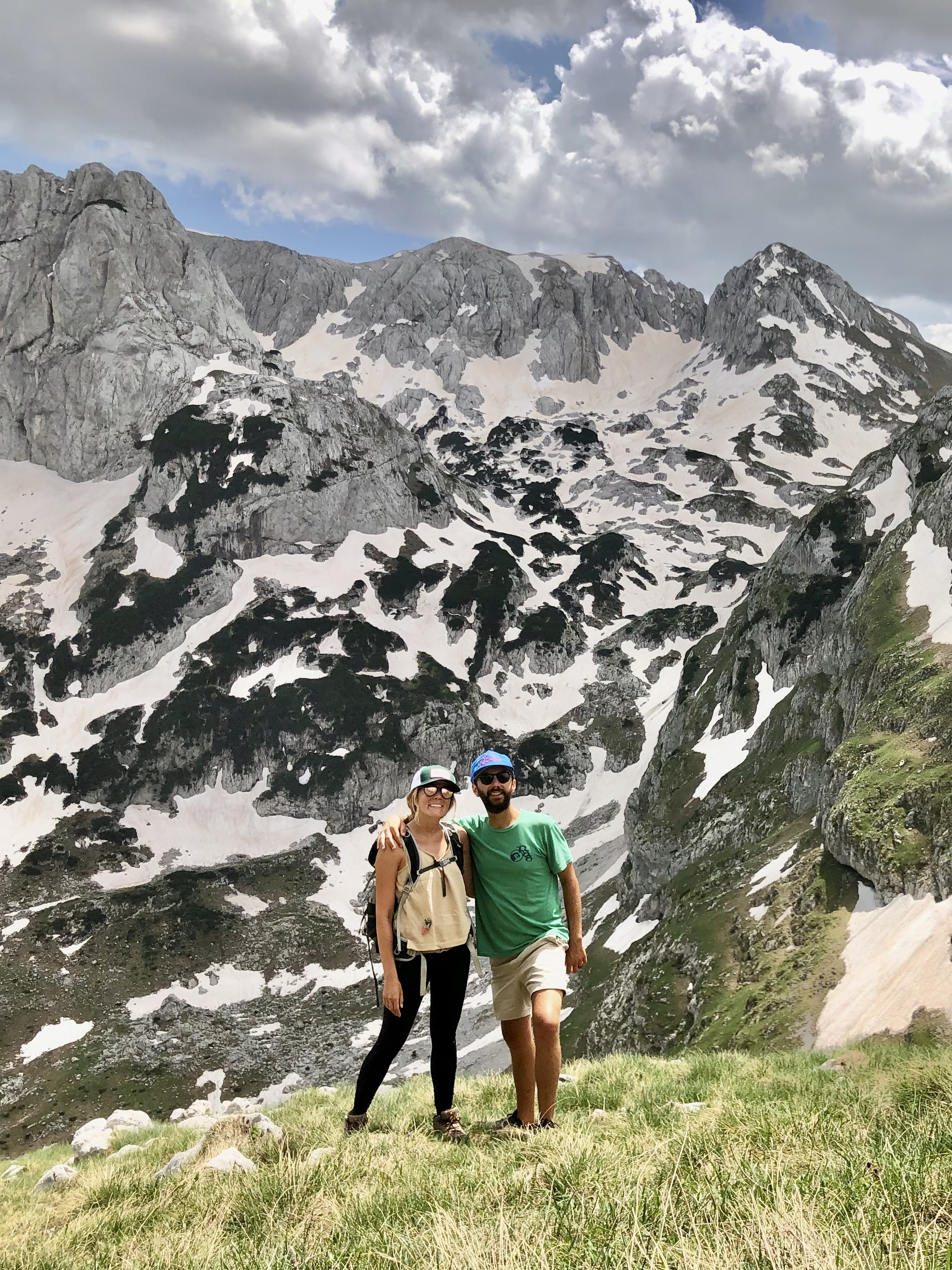 Caroline and Jonathan hiking in Montenegro with snowy mountains. 