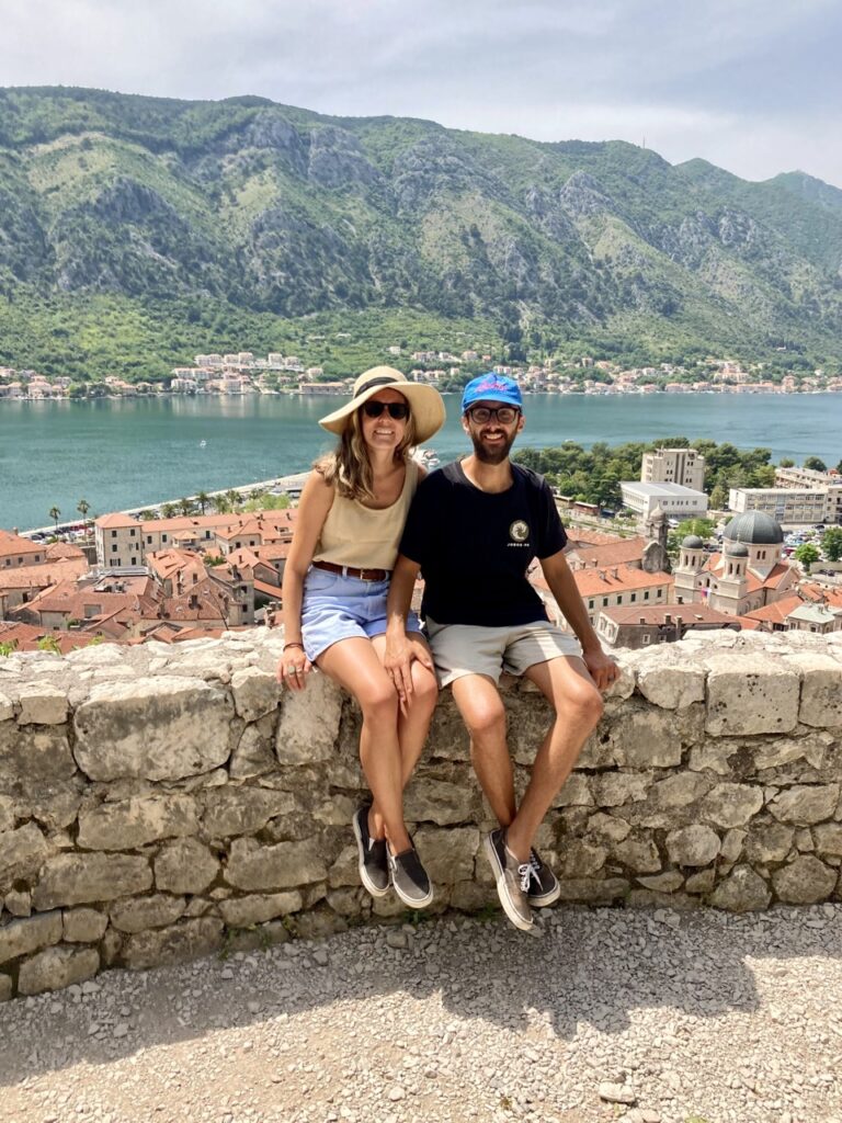 10 Most Beautiful Places in Montenegro - caroline and jonathan with old city and hill backdrop