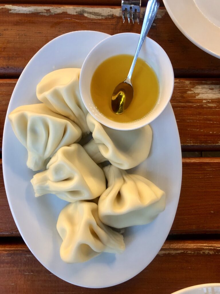 tan colored dumpling on a white plate with yellow butter in a dish. 