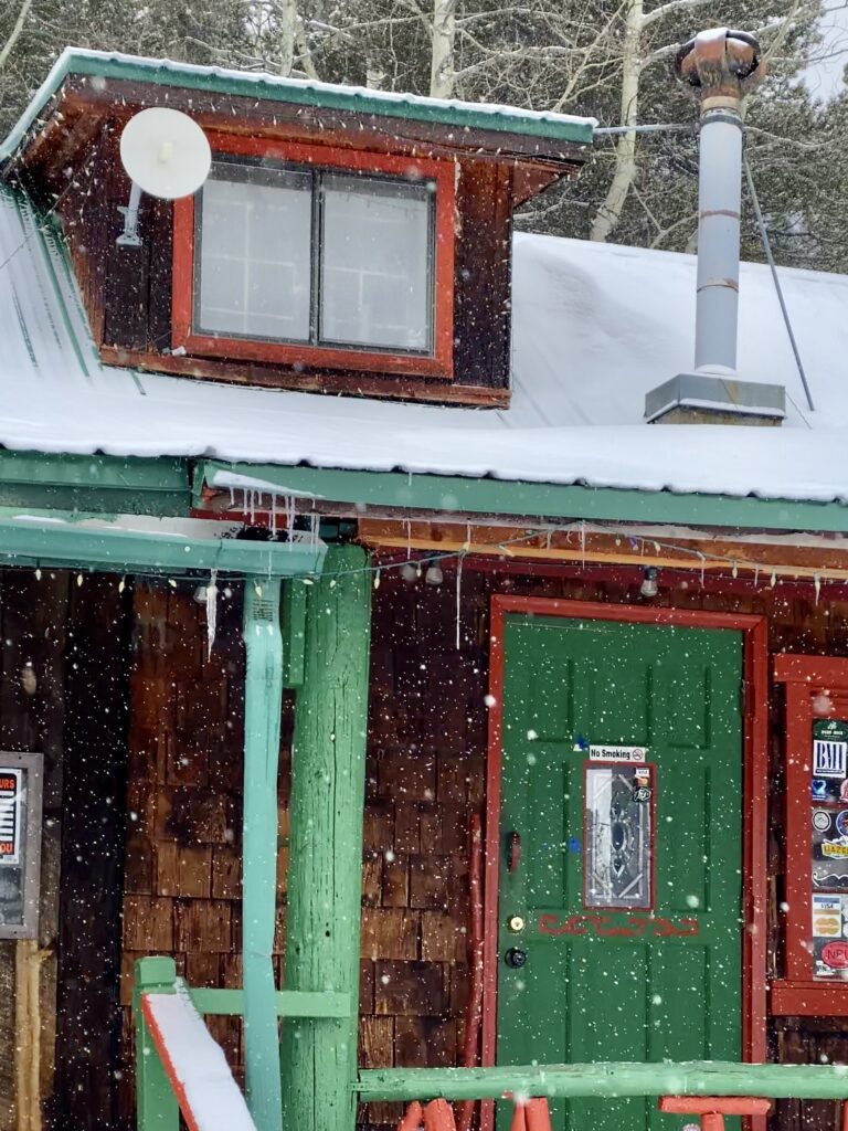 snowy green and red wooden cabin