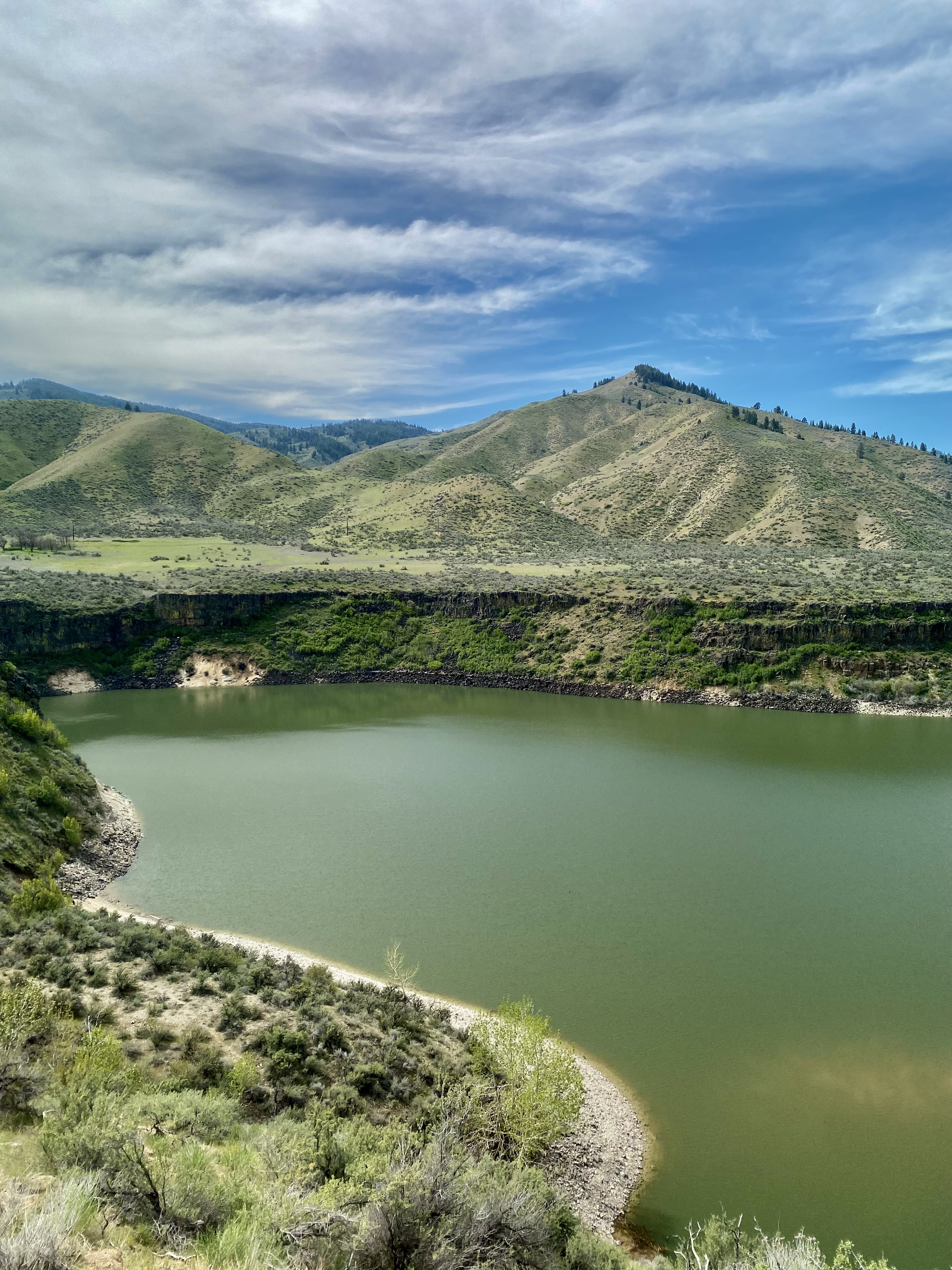 guide to the best outdoor activities around boise, idaho. green lake with mountains and cloudy blue sky in the background. 