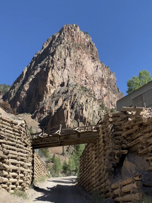 Wooden bridge sits in front of a brown rock. small towns on a colorado road trip. 